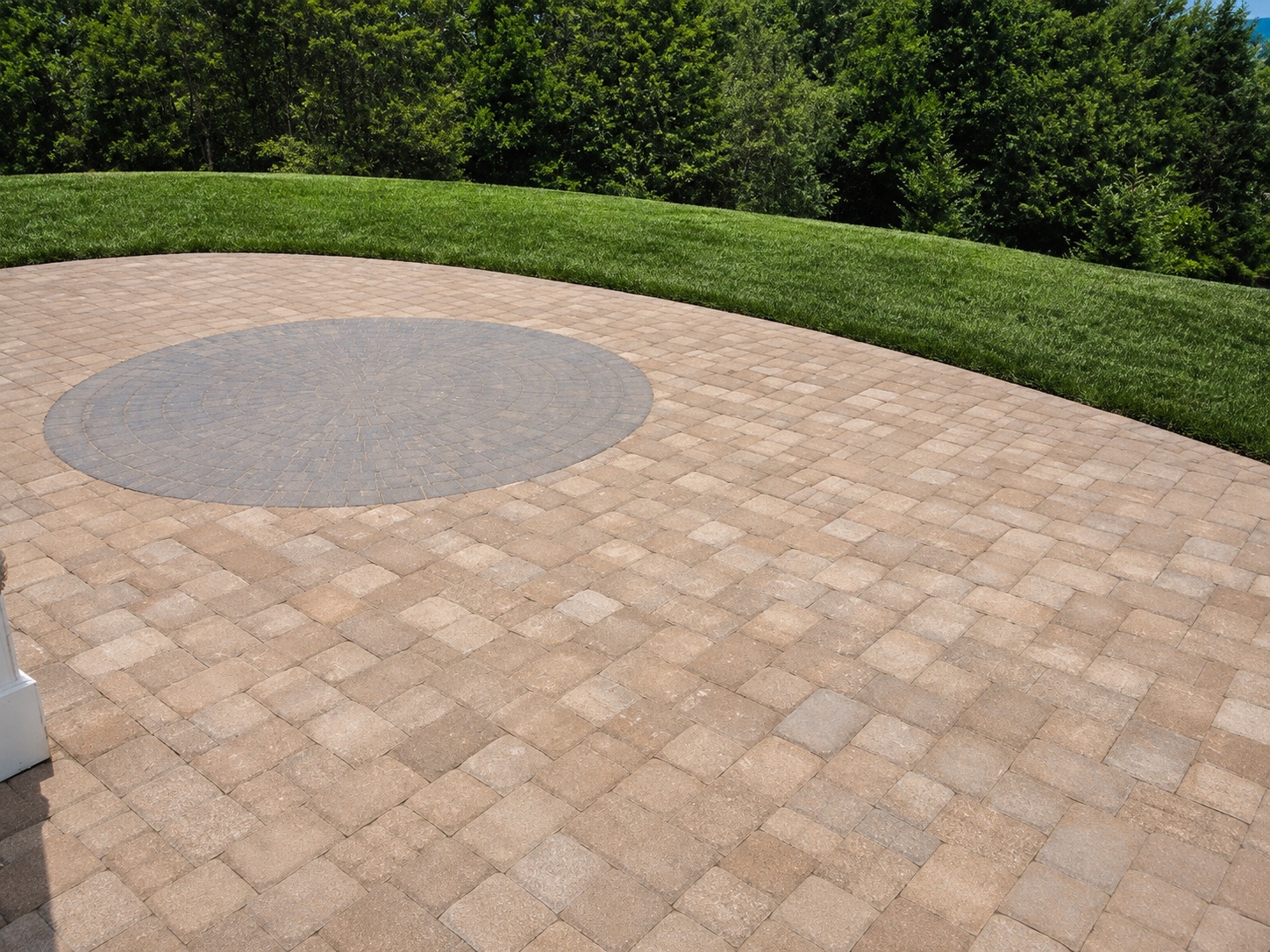 Paver patio with a circular accent inlay set into a broad outdoor surface.