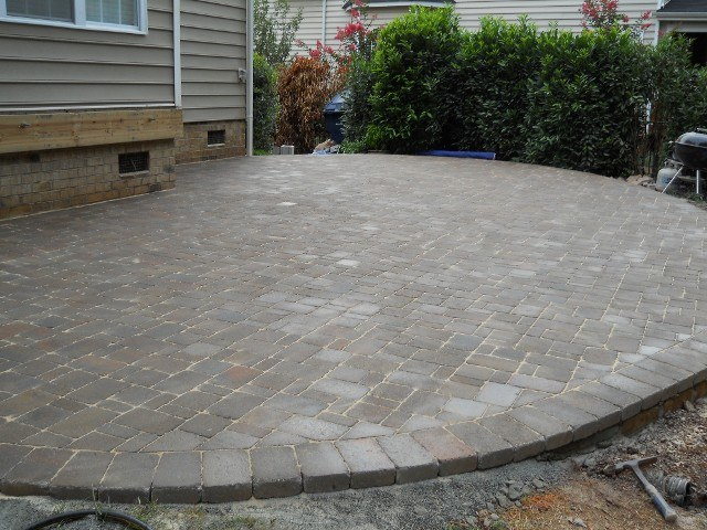 Curved paver patio with a rounded outer edge and compact backyard layout.