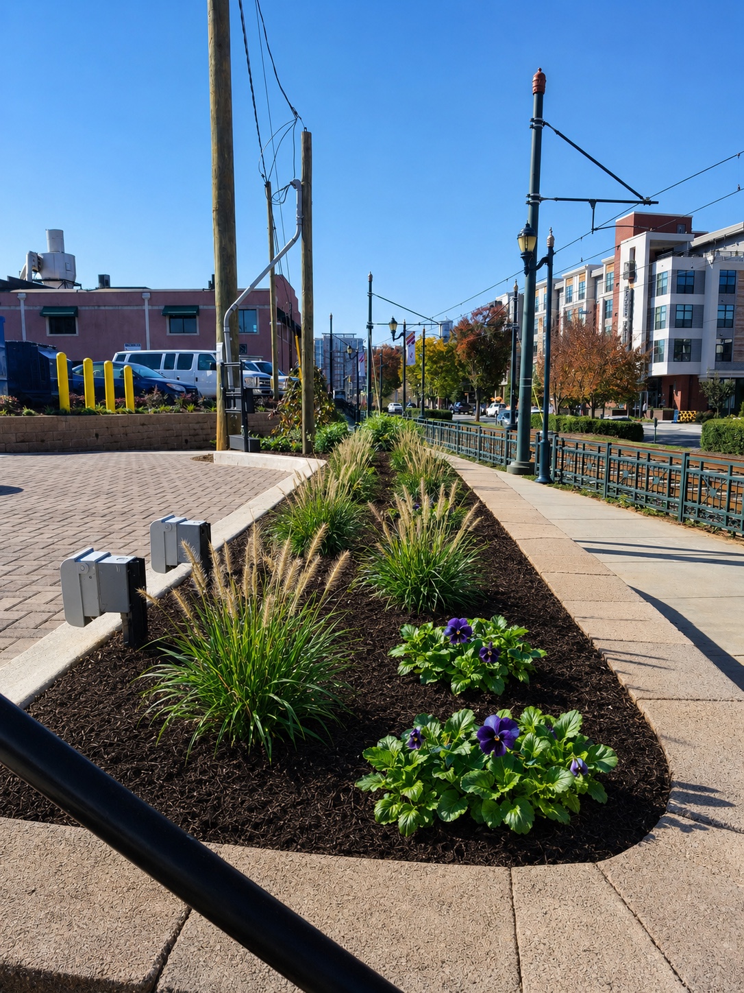 Urban hardscape edge with planting bed, concrete walk, and streetscape improvements.