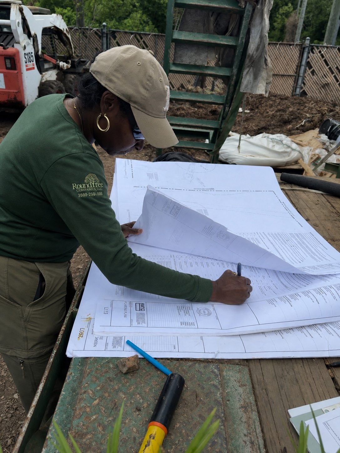 Roundtree team member reviewing project plans onsite during landscape planning and field coordination.