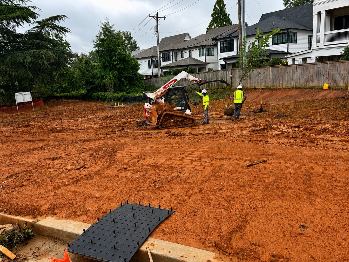 Tree installation in progress with skid steer support and coordinated field crew activity.