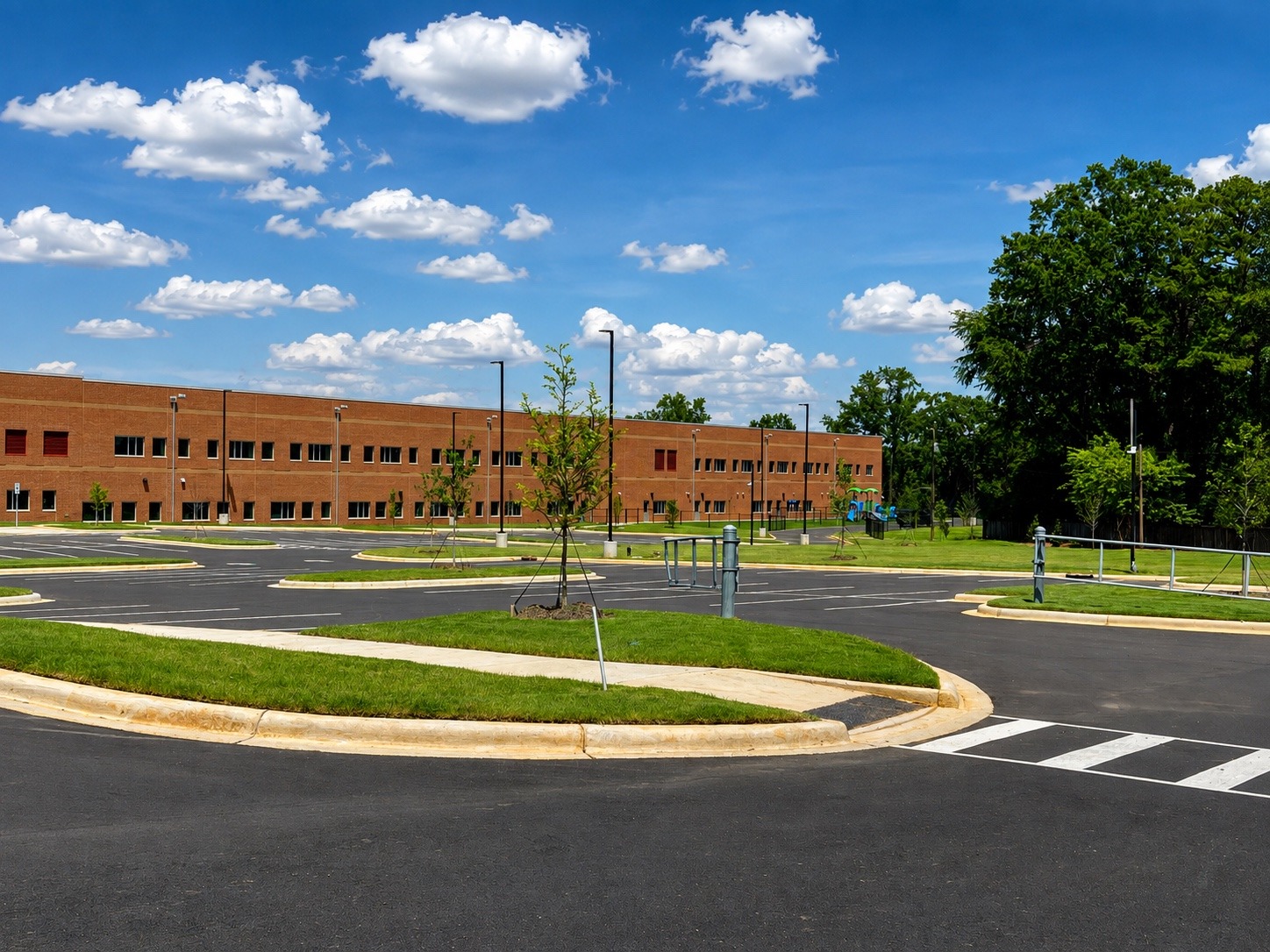 Completed school campus landscape with turf establishment and ornamental tree installation around parking areas.