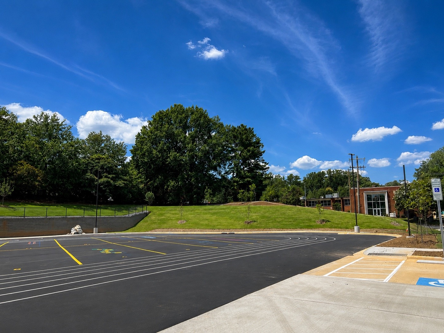 Completed school landscape with established turf around the track, parking and sloped planting areas.