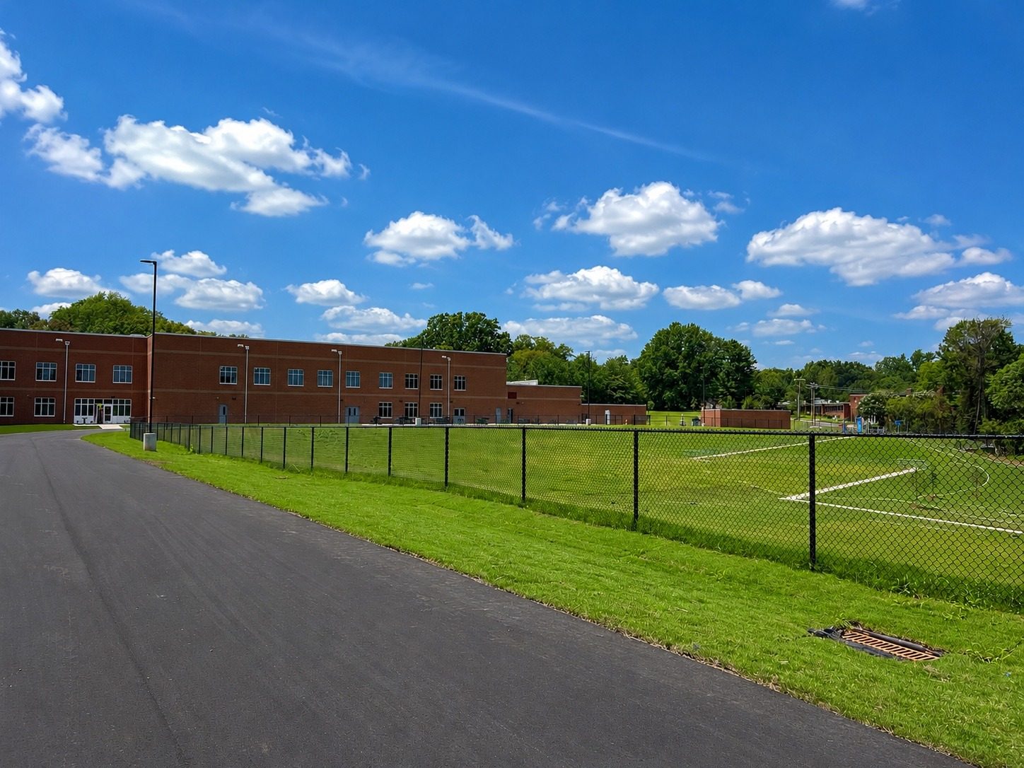 Established turf and site restoration around a school athletic field and perimeter fencing.